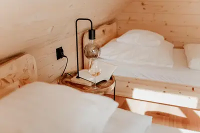 a small room with a bed and a lamp on a table at Babiogórska Chata - dom z bali z jacuzzi i sauną in Zawoja