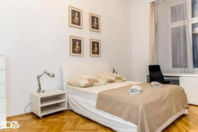 a white bedroom with a bed and a chair at P&J Apartments Floriańska in Kraków