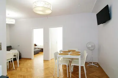 a white dining room with a table and chairs at P&J Apartments Floriańska in Kraków