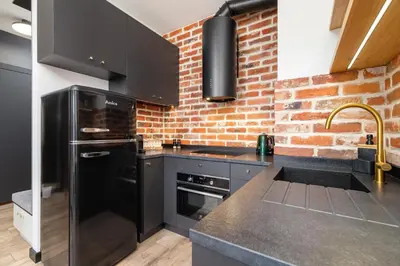 a kitchen with black appliances and a brick wall at Solaris Park Apartment Tauron Arena by Renters Prestige in Kraków