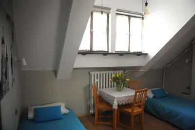 a room with a table and two beds and a window at Dom Casimi in Kraków