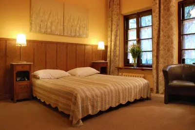 a bedroom with a bed and a chair and two windows at Dom Casimi in Kraków