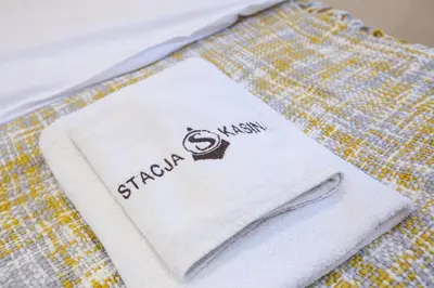 a white towel with the word stitch on it on a bed at Apartamenty Stacja Kasina in Kasina Wielka