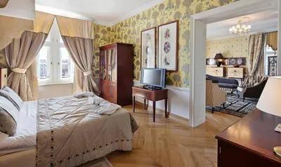 a bedroom with a bed and a desk with a television at The Bonerowski Palace Boutique Hotel in Kraków