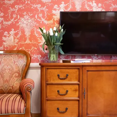 a television on a dresser with a vase of flowers at The Bonerowski Palace Boutique Hotel in Kraków