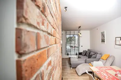 a brick wall in a living room with a couch at Apartament na Skarpie in Zator