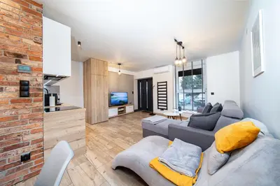 a living room with a gray couch and a brick wall at Apartament na Skarpie in Zator