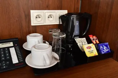 a coffee maker and cups on a counter next to a phone at Hotel Downtown Kraków in Kraków