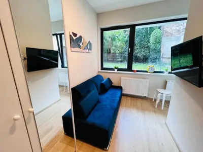a living room with a blue couch and a window at CozyStudio with Sauna in Kraków
