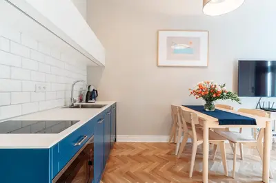 a kitchen with blue cabinets and a table with chairs at Kochanowskiego Family Apartments in Kraków