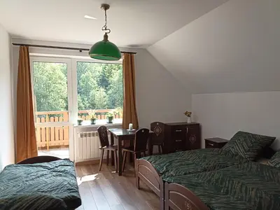 a bedroom with two beds and a table and a window at Dom Dobre Miejsce in Zawoja