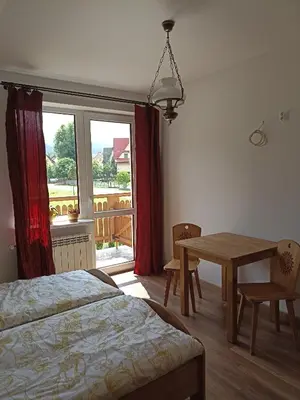 a bedroom with a bed and a table and a window at Dom Dobre Miejsce in Zawoja
