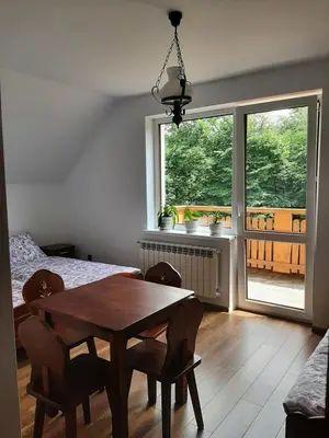 a dining room with a wooden table and a window at Dom Dobre Miejsce in Zawoja