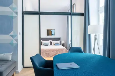 a bedroom with a bed and a blue chair at Cadena Gallery Apartments Wyspiański in Kraków