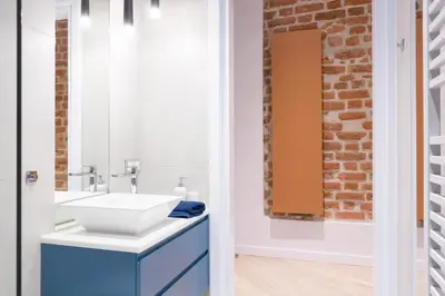 a bathroom with a sink and a brick wall at Cadena Gallery Apartments Wyspiański in Kraków