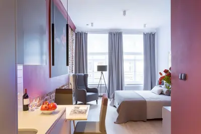 a hotel room with a bed and a desk and a bed and a window at Cadena Gallery Apartments Matejko in Kraków