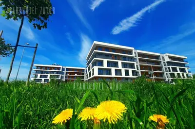 a tall building with yellow flowers in the grass at Aparthotel ZATOR Glam 52 jacuzzi in Zator
