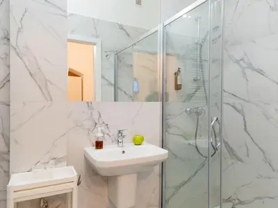 a white bathroom with a sink and a shower at Apartamenty Nikodem in Old Town - Krakow center in Kraków