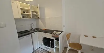 a small white kitchen with a sink and a chair at Apartamenty Nikodem in Old Town - Krakow center in Kraków