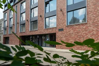 a red brick building with glass windows at Cozy Studio Apartments Sauna & AC Kraków by Noclegi Renters in Kraków