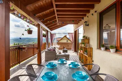 a patio with a table and chairs on a balcony at Dom z Widokiem Mucharz 405 in Mucharz