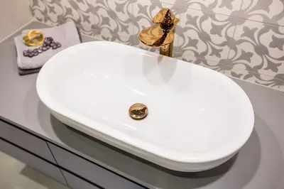 a white bathroom sink with a gold faucet at Cadena Gallery Apartments Mehoffer in Kraków