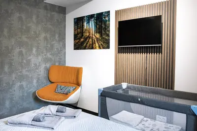 a bedroom with a bed and a chair and a television at Premium Apartment Eleven in Zator
