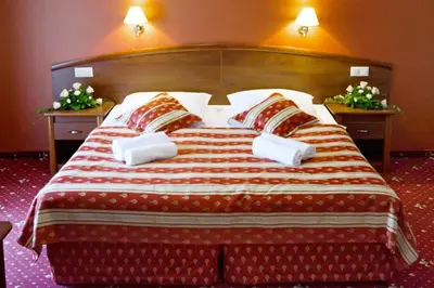 a large bed with a red and white blanket and pillows at Hotel Novum & Spa in Niepołomice