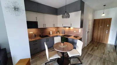a kitchen with a wooden table and white chairs at Apartament 20 Zator in Zator