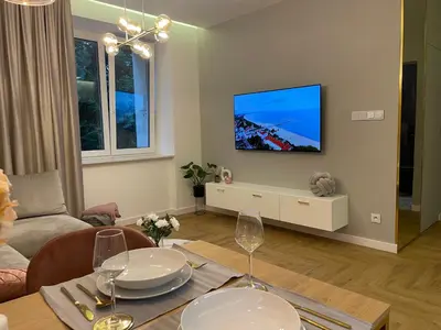 a living room with a table and a television on a wall at CRYSTAL CAVE Apartment in Wieliczka