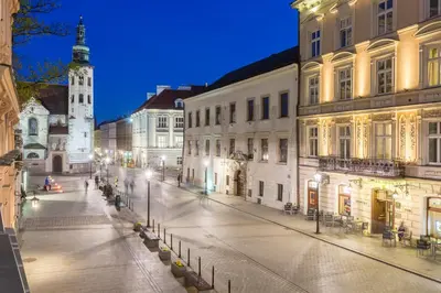 an empty city street at night with a clock tower at Cadena Gallery Apartments Witkacy in Kraków