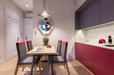 a dining room with a table and chairs and a kitchen at Cadena Gallery Apartments Witkacy in Kraków