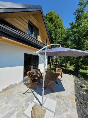 a patio with an umbrella and a table and chairs at Widokówka in Zawoja