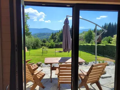 a patio with chairs and a table and an umbrella at Widokówka in Zawoja