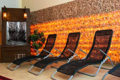 four chairs in a waiting room with a wall of flowers at Korona Żywca - MADOHORA in Ślemień