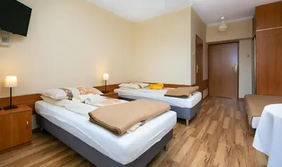 a hotel room with three beds and a television at Korona Żywca - MADOHORA in Ślemień