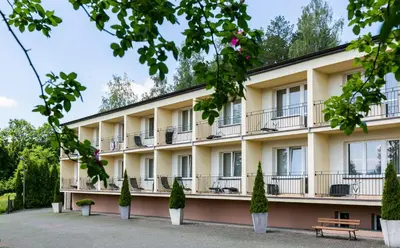 an apartment building with balconies and trees at Korona Żywca - MADOHORA in Ślemień