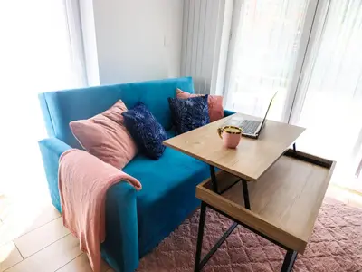 a blue couch with a table with a laptop on it at Sander Apartments in Kraków