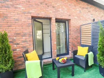 a patio with two chairs and a table with yellow pillows at Sander Apartments in Kraków