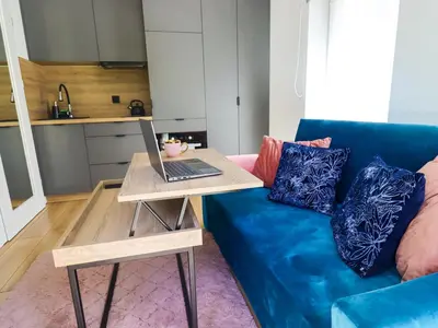 a living room with a blue couch and a laptop on a table at Sander Apartments in Kraków