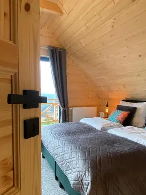 two beds in a room with a wooden ceiling at Ovis Homes in Zawoja