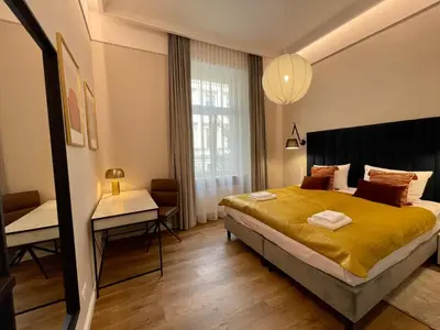 a bedroom with a large bed and a desk at Golden Queen Apartments City Center in Kraków