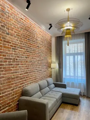 a living room with a couch and a brick wall at Golden Queen Apartments City Center in Kraków