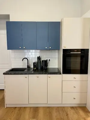 a white kitchen with blue cabinets and a sink at Golden Queen Apartments City Center in Kraków