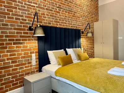 a bedroom with a bed and a brick wall at Golden Queen Apartments City Center in Kraków