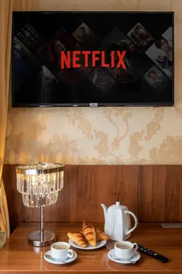 a table with two cups and croissants and a netflix sign at David Boutique ApartHotel in Kraków