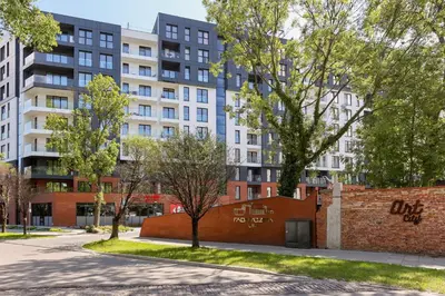 a brick wall and trees in front of buildings at Fabryczna City Kraków by Renters by Noclegi Renters in Kraków