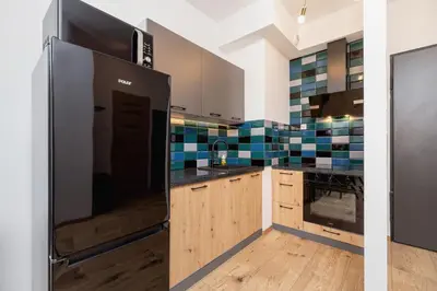 a kitchen with a stainless steel refrigerator and wooden cabinets at Fabryczna City Kraków by Renters by Noclegi Renters in Kraków