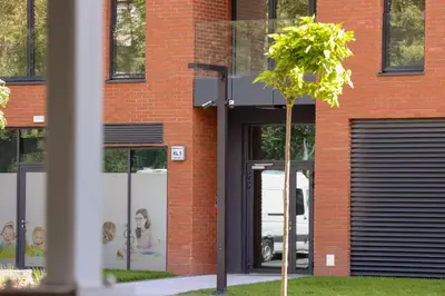 a red brick building with two garage doors and a tree at Fabryczna City Kraków by Renters by Noclegi Renters in Kraków