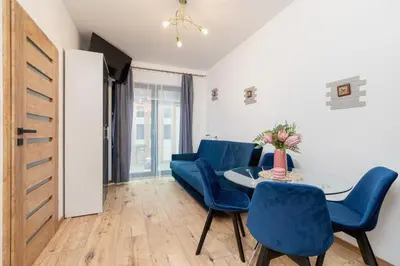 a living room with blue chairs and a table at Fabryczna City Kraków by Renters by Noclegi Renters in Kraków